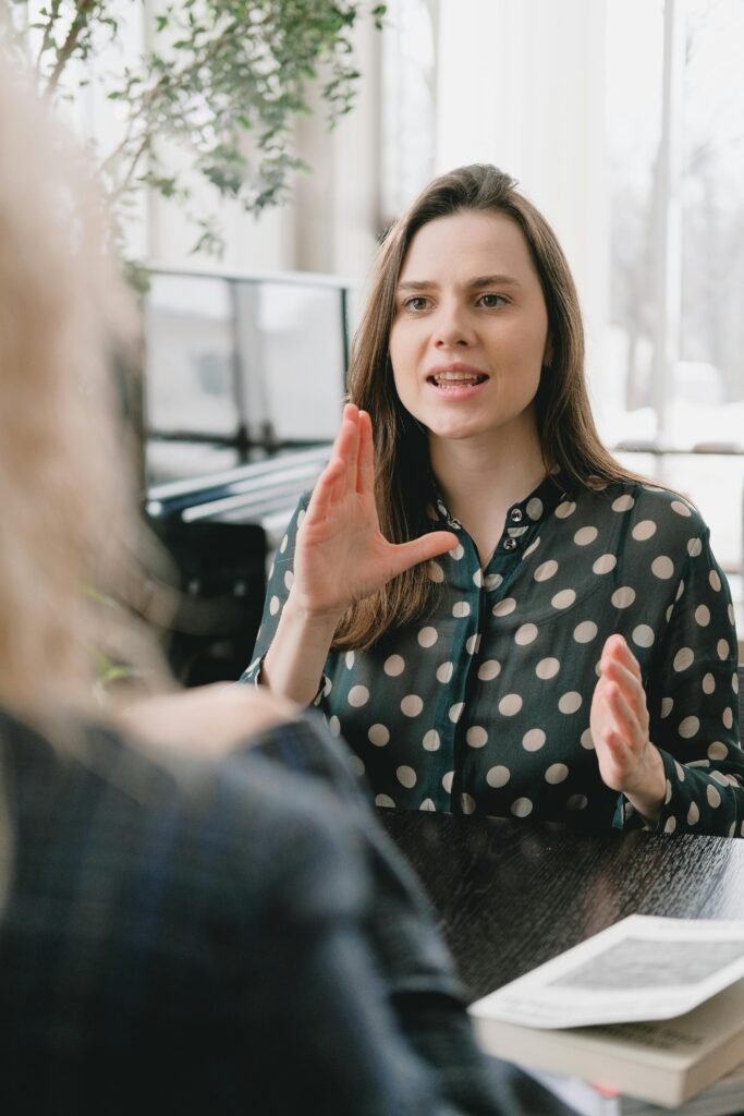 pexels-photo-7516279-7516279 Focused woman in a polka dot blouse engages in a conversation indoors.